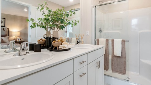 Lowrie Estates primary bathroom with two sink vanity and a walk in sliding glass door shower