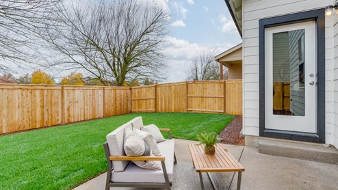 Lowrie Estates grass landscaped backyard with patio and outdoor furniture