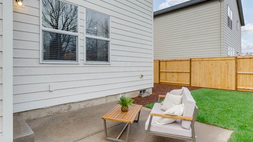 Lowrie Estates grass landscaped backyard with patio and outdoor furniture
