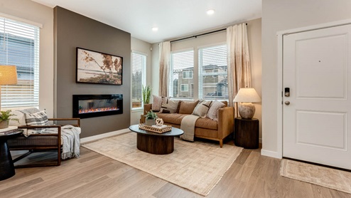 Scholls Meadow Great room with laminate flooring, rug, oval coffee table, brown couch with cushions and pillows, electric fireplace, tv, side table, and windows