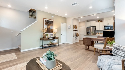 Scholls Meadow great room with coffee table, rug, tv, laminate flooring, kitchen table, view of kitchen