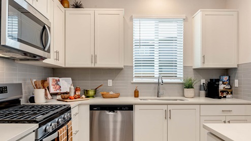 Scholls Meadow Kitchen with stools, kitchen island, stainless steel appliances, quartz countertops, white shaker cabinets, windows