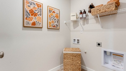Scholls Meadow laundry room with paintings, white wire shelving, and basket, and hamper