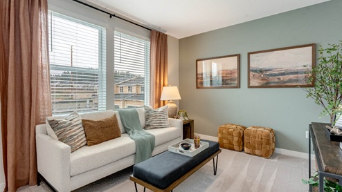 Scholls Meadow staged bedroom with white couch, teal accent wall, white carpet, black coffee table, and lamp