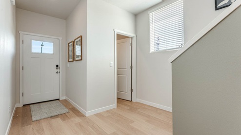 Davis Estates entry with view of front door, painting, stairs, powder room, and laminate flooring