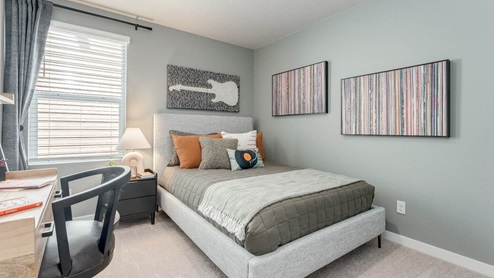 Davis Estates bedroom with side table and a lamp, bed, paintings, desk with a chair, and window with shades
