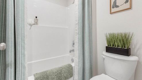 Davis Estates secondary bathroom with toilet, shower tub, white toilet with a plant