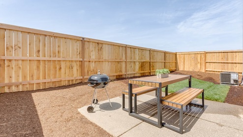 Davis Estates backyard with a table, bark dust, a fence, and grass