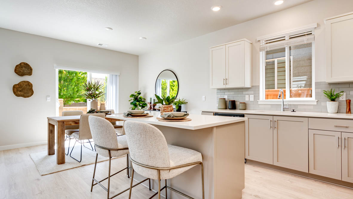 Davis Estates Kitchen with island, barstool chairs, quartz countertops, stainless steel appliances, windows, laminate flooring, and view of the dining room