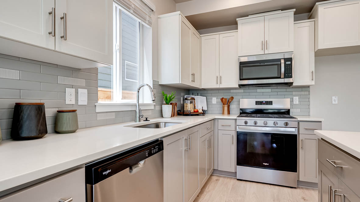 Davis Estates Kitchen with island, barstool chairs, quartz countertops, stainless steel appliances, windows, and laminate flooring