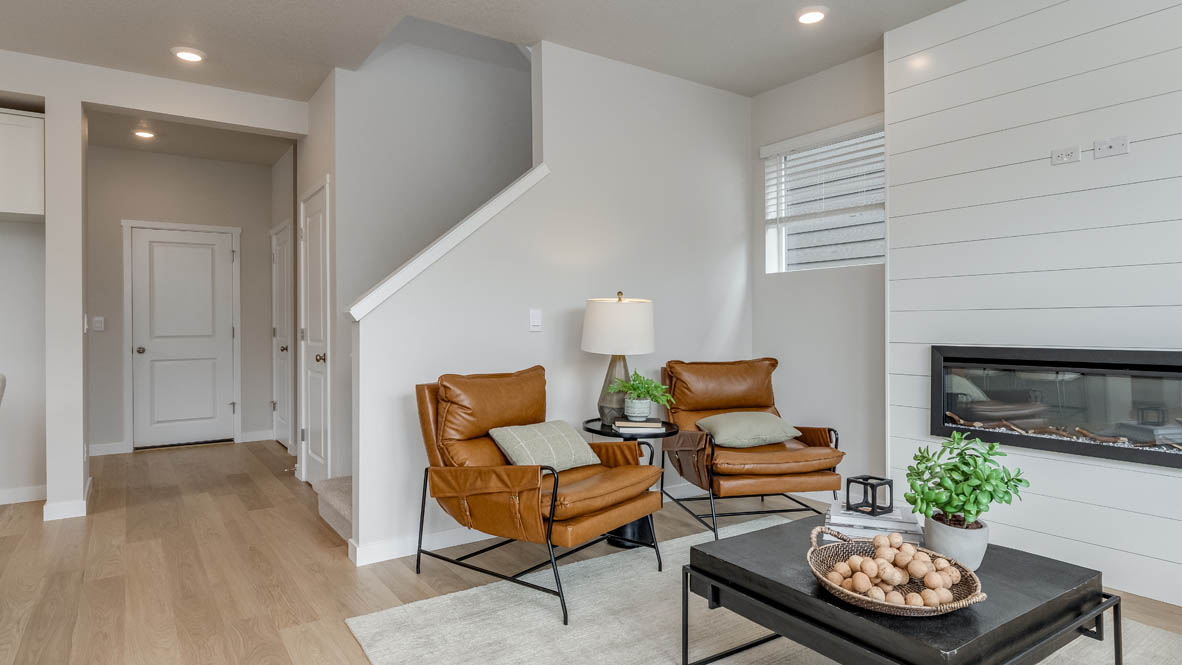 Davis Estates Great Room with electric fireplace, black coffee table, orange chair, carpet, and laminate flooring