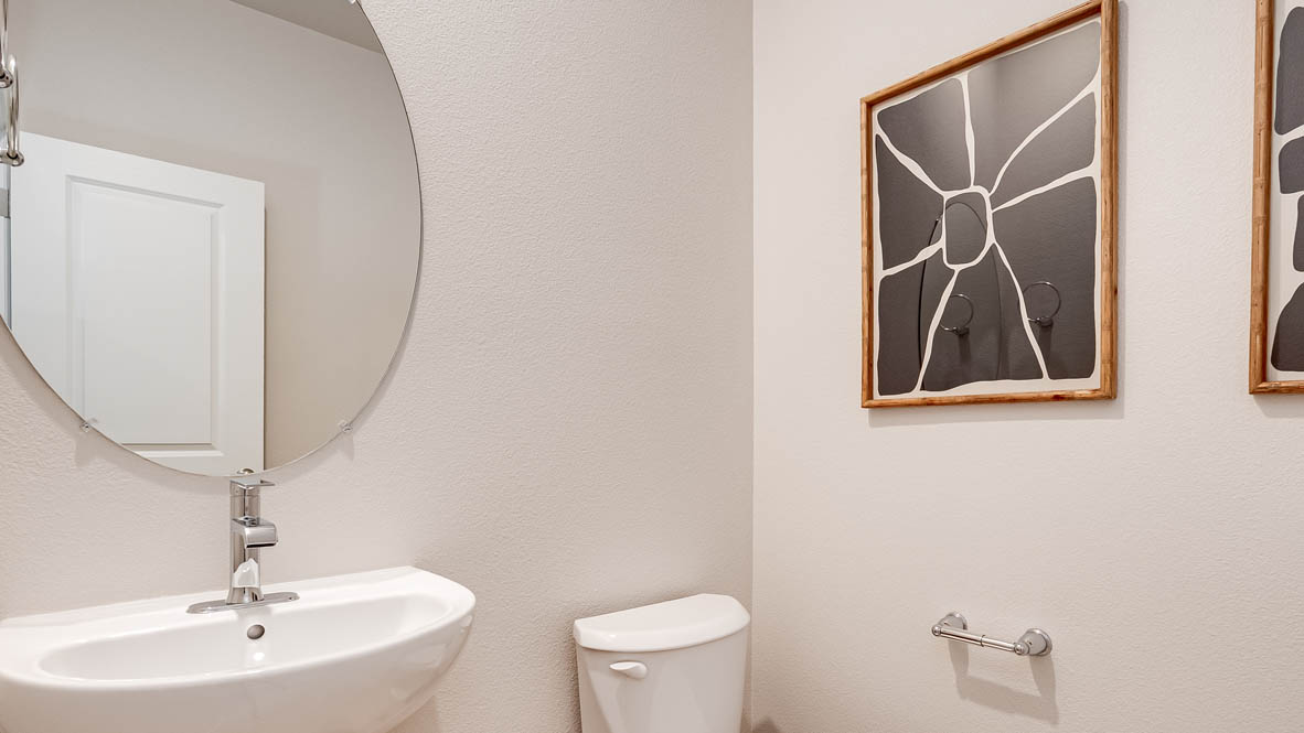 Davis Estates Powder Room with circular mirror, single sink vanity, toilet, and paintings