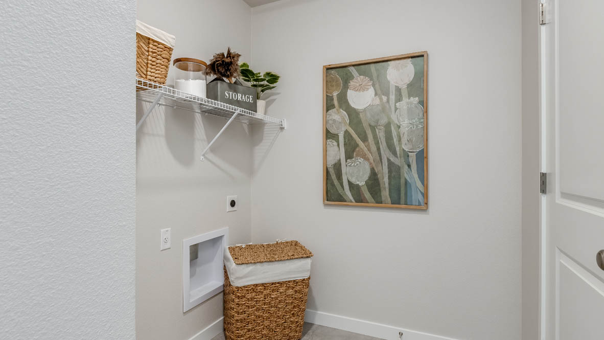 Davis Estates laundry room with a hamper, paintings, and white wire shelving