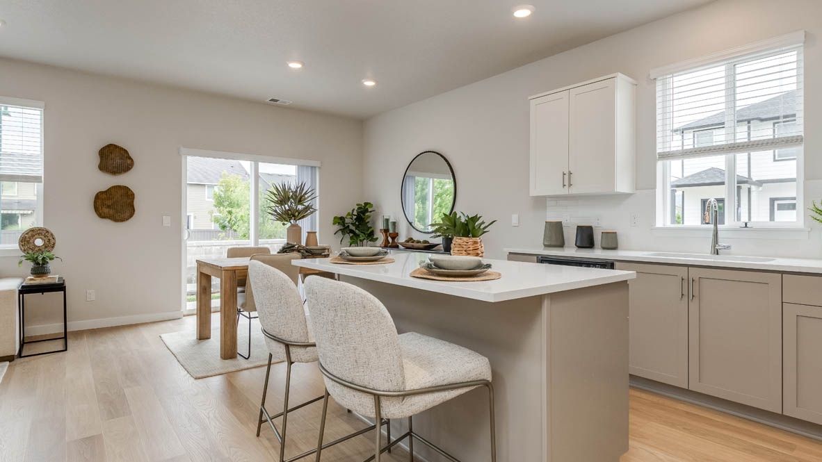 Davis Estates Kitchen with island, barstool chairs, quartz countertops, stainless steel appliances, windows, laminate flooring, and view of the dining room