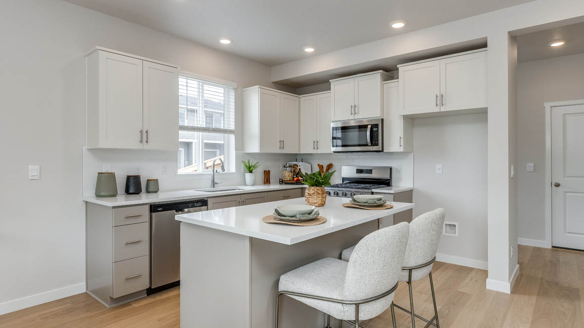 Davis Estates Kitchen with island, barstool chairs, quartz countertops, stainless steel appliances, windows, and laminate flooring