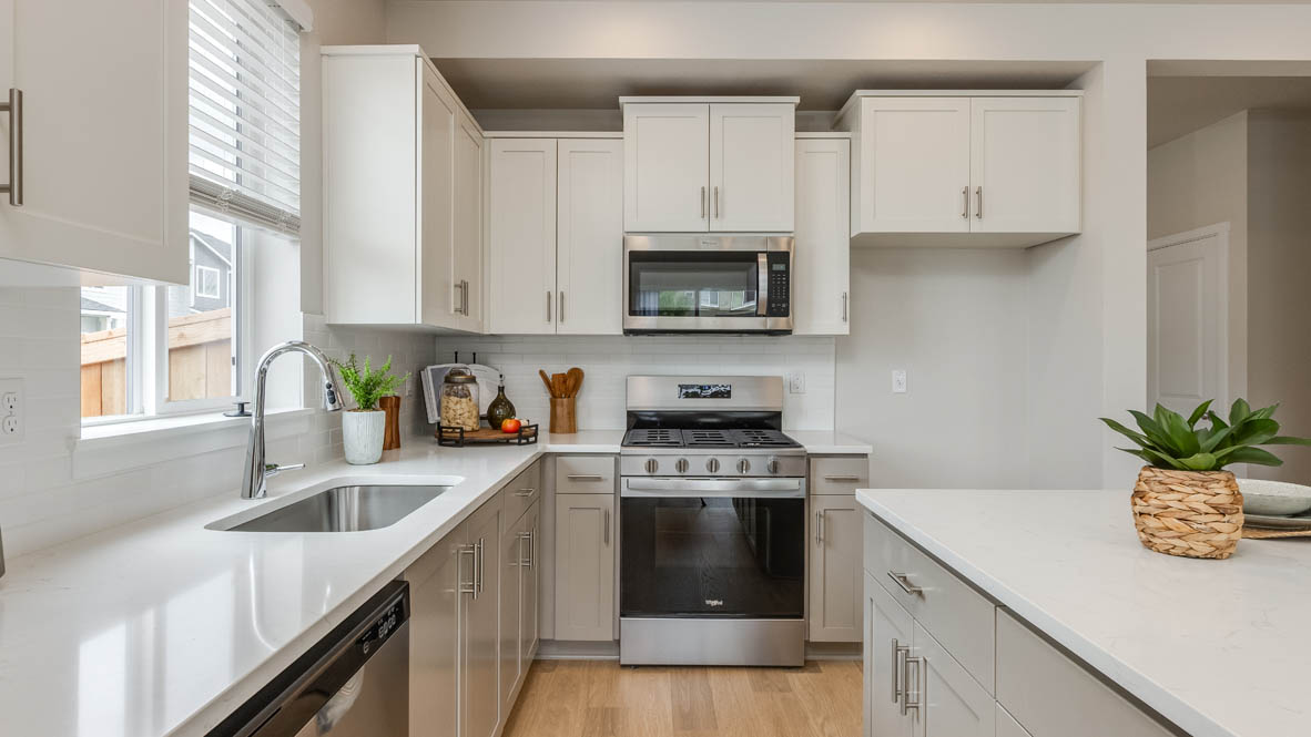 Davis Estates Kitchen with island, barstool chairs, quartz countertops, stainless steel appliances, windows, and laminate flooring