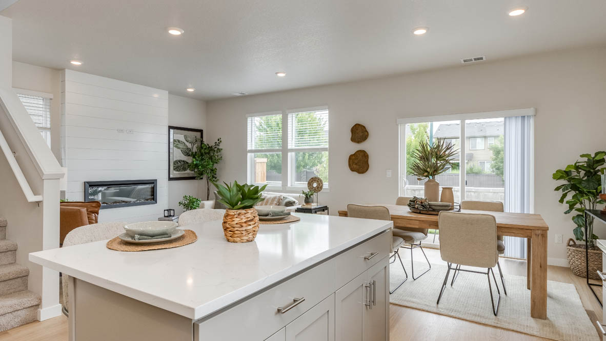 Davis Estates Kitchen with island, barstool chairs, quartz countertops, cabinets, windows, laminate flooring, and view of the great room