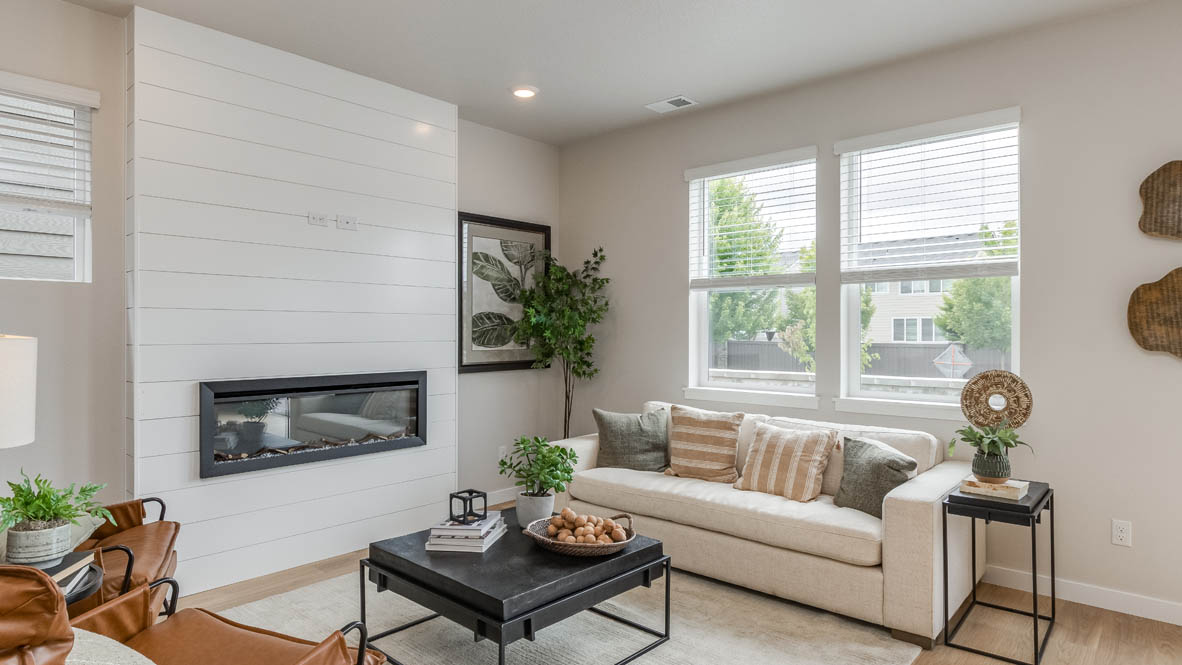 Davis Estates Great Room with electric fireplace, white couch, black coffee table, windows, orange chair, carpet, and laminate flooring