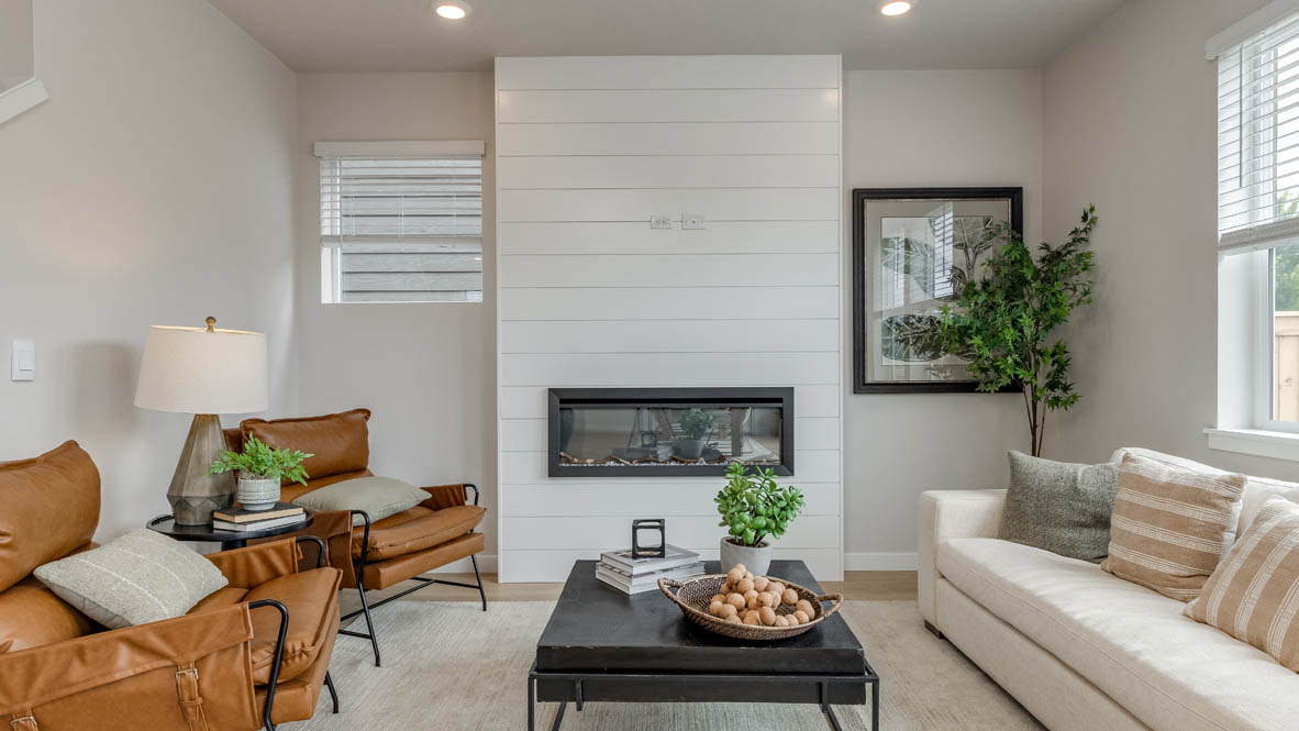 Davis Estates Great Room with electric fireplace, white couch, black coffee table, windows, orange chair, carpet, and laminate flooring
