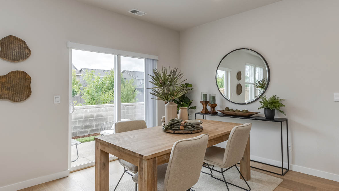 Davis Estates Dining Room with light wooden table, decorative center plant, four chairs, carpet, mirror with end table, and sliding glass door