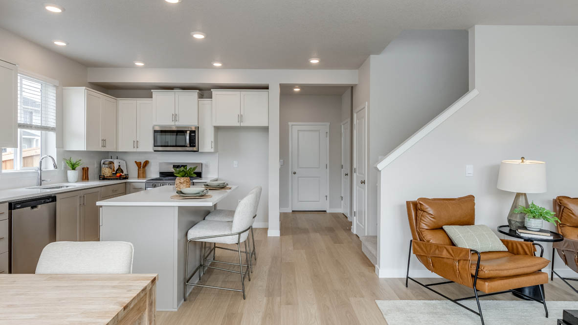 Davis Estates Great room and dining room with laminate flooring, table with chairs, orange chairs, lamp, with view of the kitchen and stairs