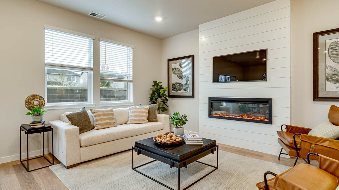Davis Estates Great Room with electric fireplace, white couch, black coffee table, windows, orange chair, carpet, and laminate flooring