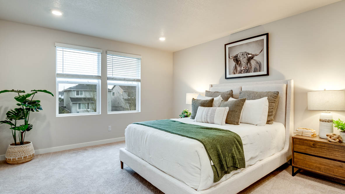 Davis Estates Primary Bedroom with white comforter and a green accent blanket, pillows, two nightstands with windows, center panting, and window