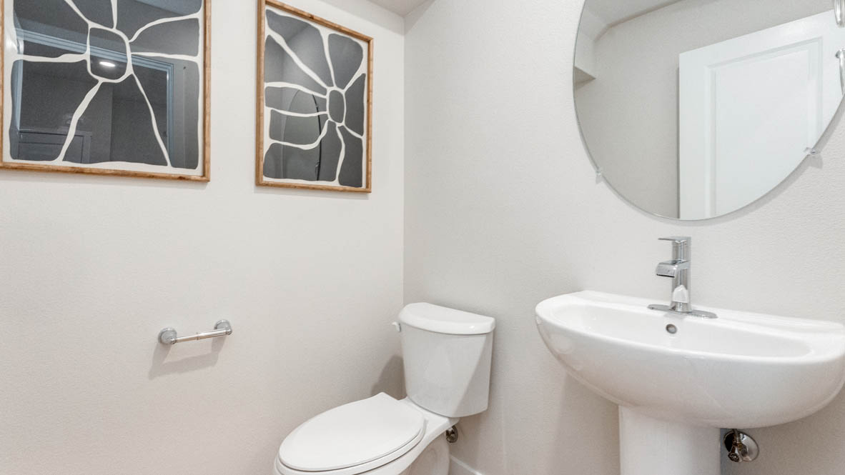 Davis Estates Powder Room with circular mirror, single sink vanity, toilet, and paintings