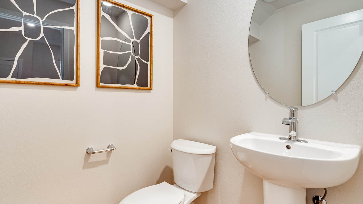 Davis Estates Powder Room with circular mirror, single sink vanity, toilet, and paintings