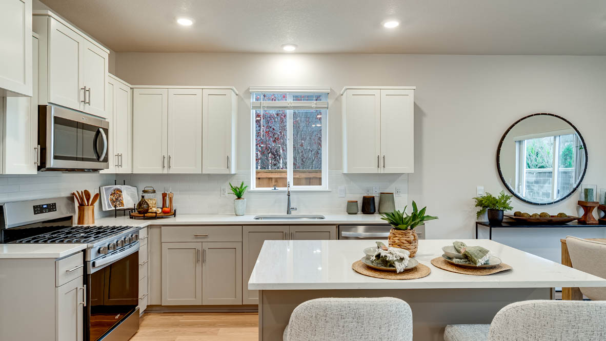 Davis Estates Kitchen with island, barstool chairs, quartz countertops, stainless steel appliances, windows, and laminate flooring