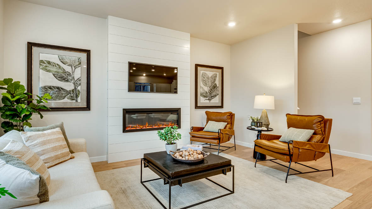 Davis Estates Great Room with electric fireplace, white couch, black coffee table, windows, orange chair, carpet, and laminate flooring
