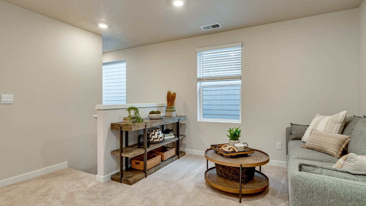 Davis Estates Loft with coffee table, gray couch, plant, three paintings, and windows