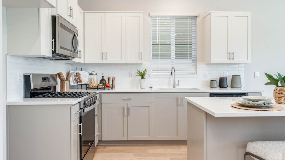 Davis Estates Kitchen with island, barstool chairs, quartz countertops, stainless steel appliances, windows, and laminate flooring