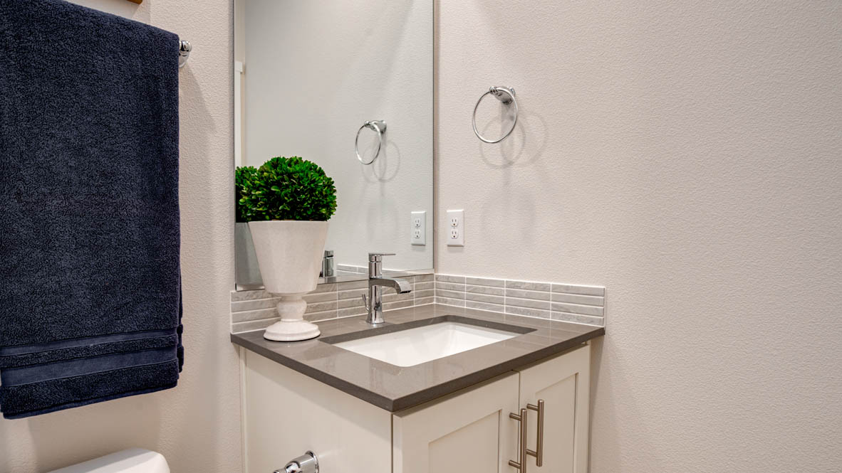 Davis Estates Downstairs bathroom with toilet, mirror, tub, and white cabinets