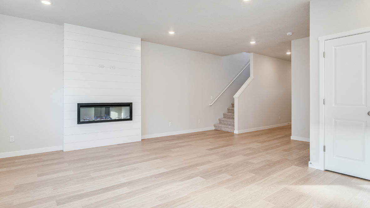 Davis Estates great room with fireplace, laminate flooring, and the stairs in the background