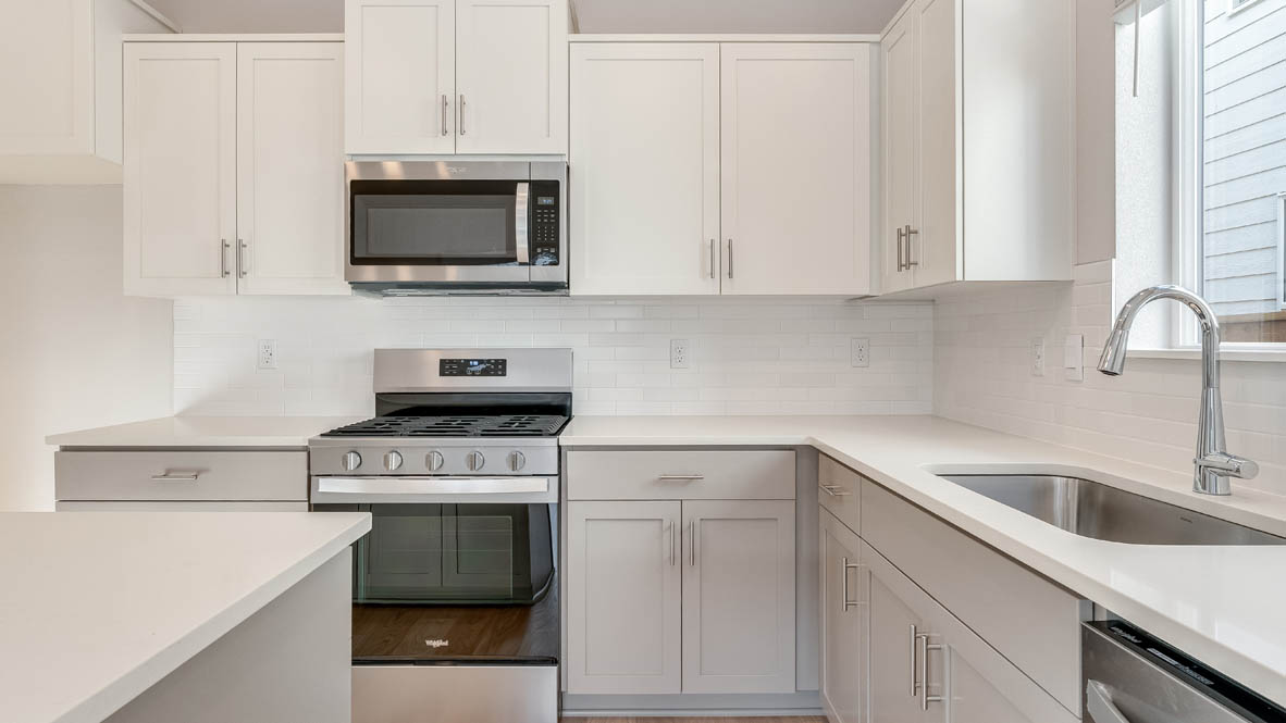 Davis Estates kitchen with laminate flooring, stainless steel appliances, cabinets, window, solid surface countertops