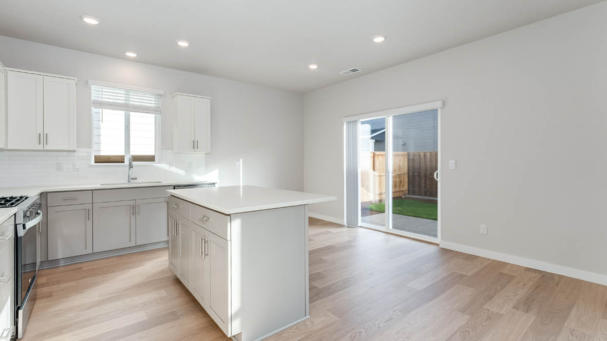 Davis Estates dining room with laminate flooring, windows, and the kitchen in the background