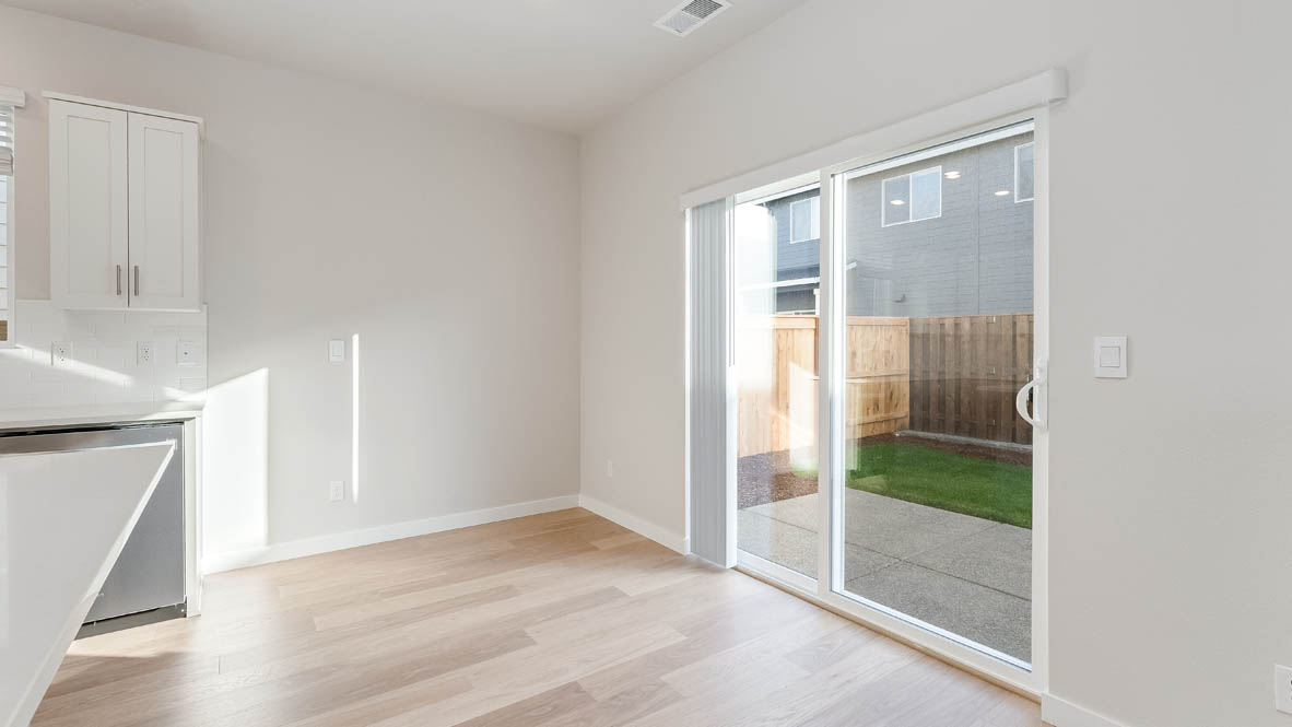 Davis Estates dining room with laminate flooring, windows, and the kitchen in the background
