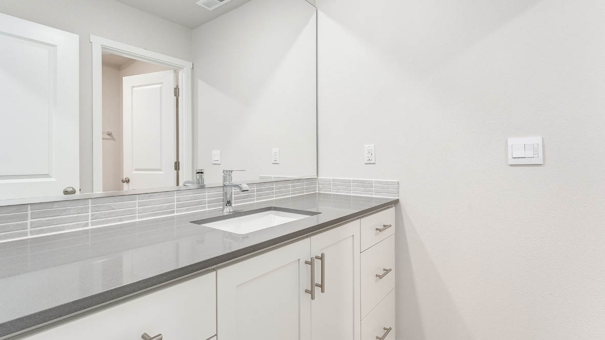 Davis estates bathroom with solid surface countertops, mirror, and cabinets