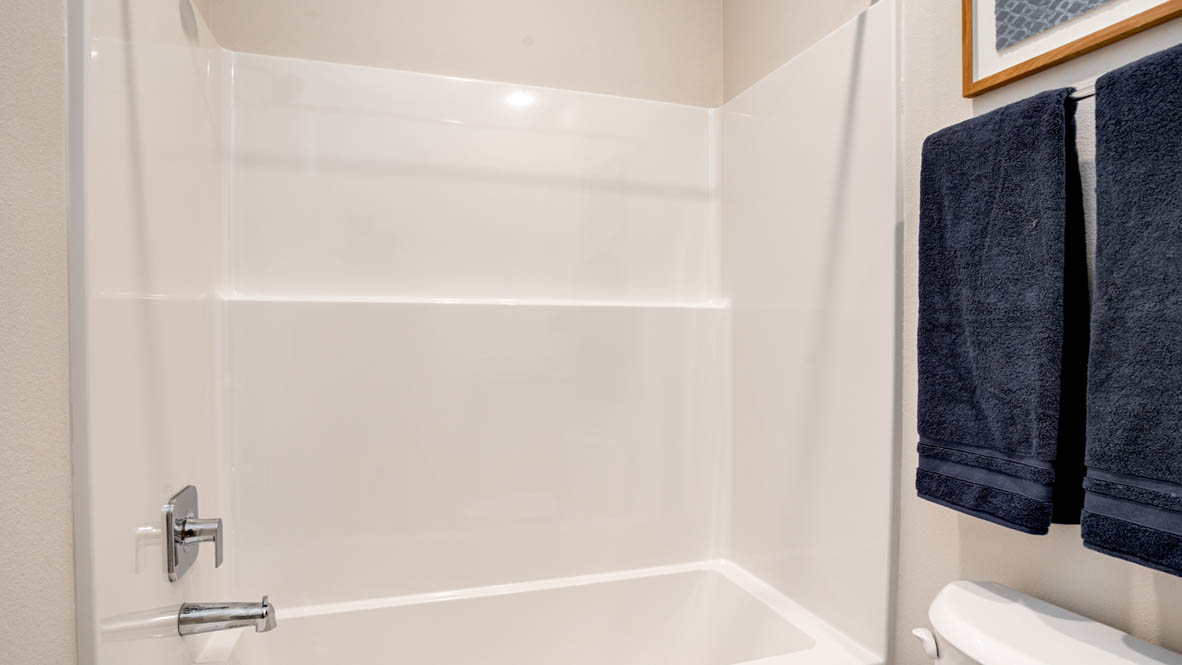 Davis Estates Downstairs bathroom with toilet, mirror, tub, and white cabinets