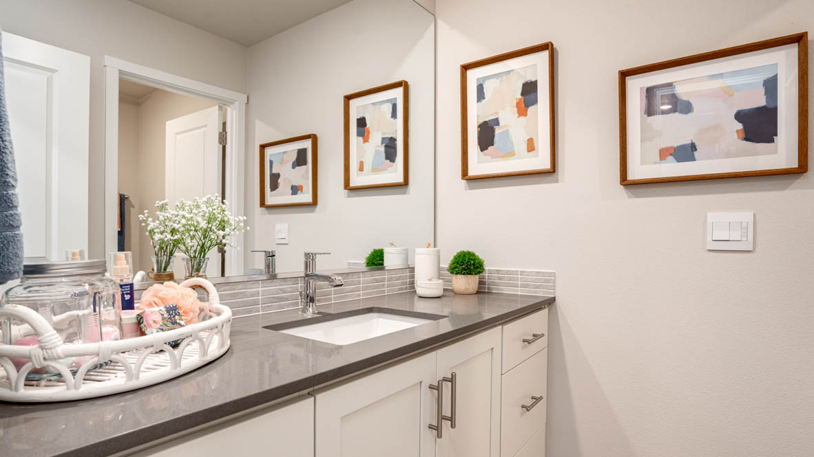Davis estates bathroom with solid surface countertops, mirror, and cabinets
