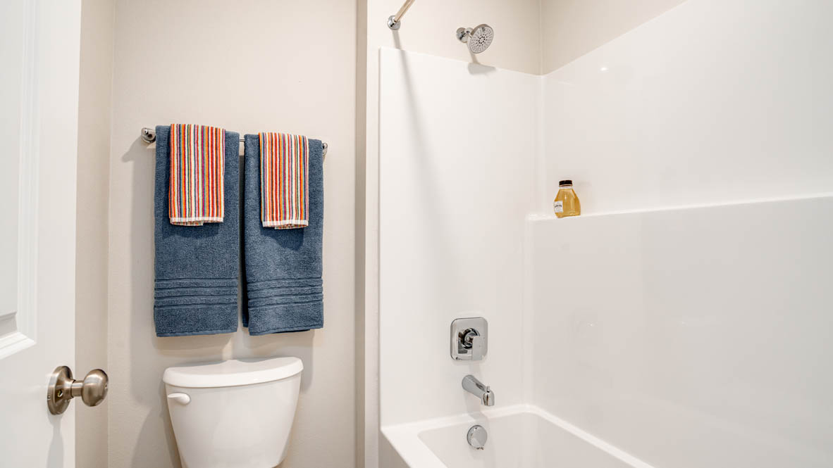 Davis Estates bathroom with toilet, and white shower tub