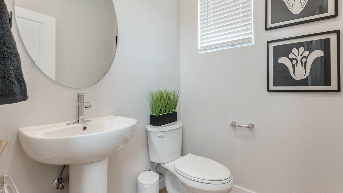 Davis estates powder room with single sink vanity, circle mirror, two paintings, window, and toilet