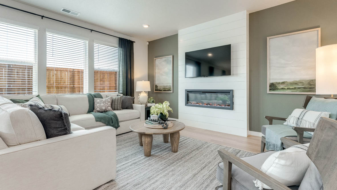 Davis Estates great room with white couch, chair, coffee table, paintings, lamp, rug, windows with curtains