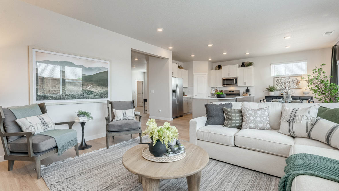 Davis Estates great room with couch, chair, coffee table, rug, and the kitchen and dining room in the background