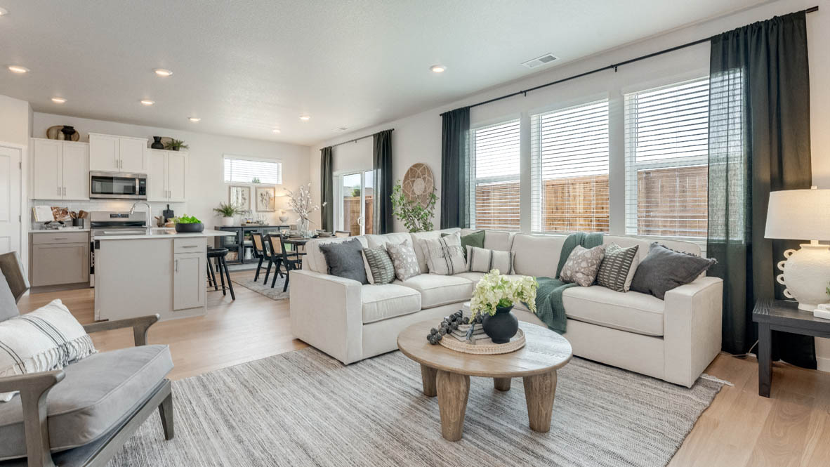 Davis Estates great room with white couch, chair, coffee table, rug, and kitchen and dining room in the background