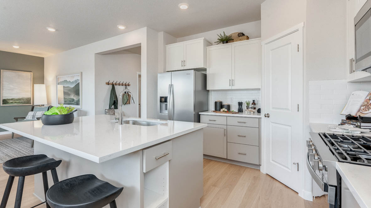 Davis Estates Kitchen with solid quartz countertops, in-island sink with a breakfast bar, stainless steel appliances, shaker style cabinets, pantry