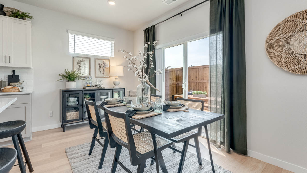 Davis Estates Dining Room with wood table with chairs, kitchen wear, sliding glass door with curtains, rug, and the great room in the background