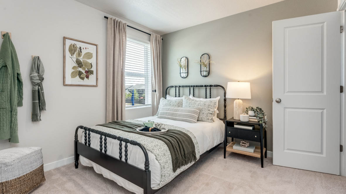 Davis Estates bedroom with side table and a lamp, bed, paintings, chair, and window with shades