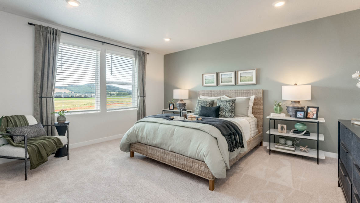 Davis Estates Primary bedroom with white carpet, three hanging paintings, two side tables, two lamps, a chair, windows with curtains